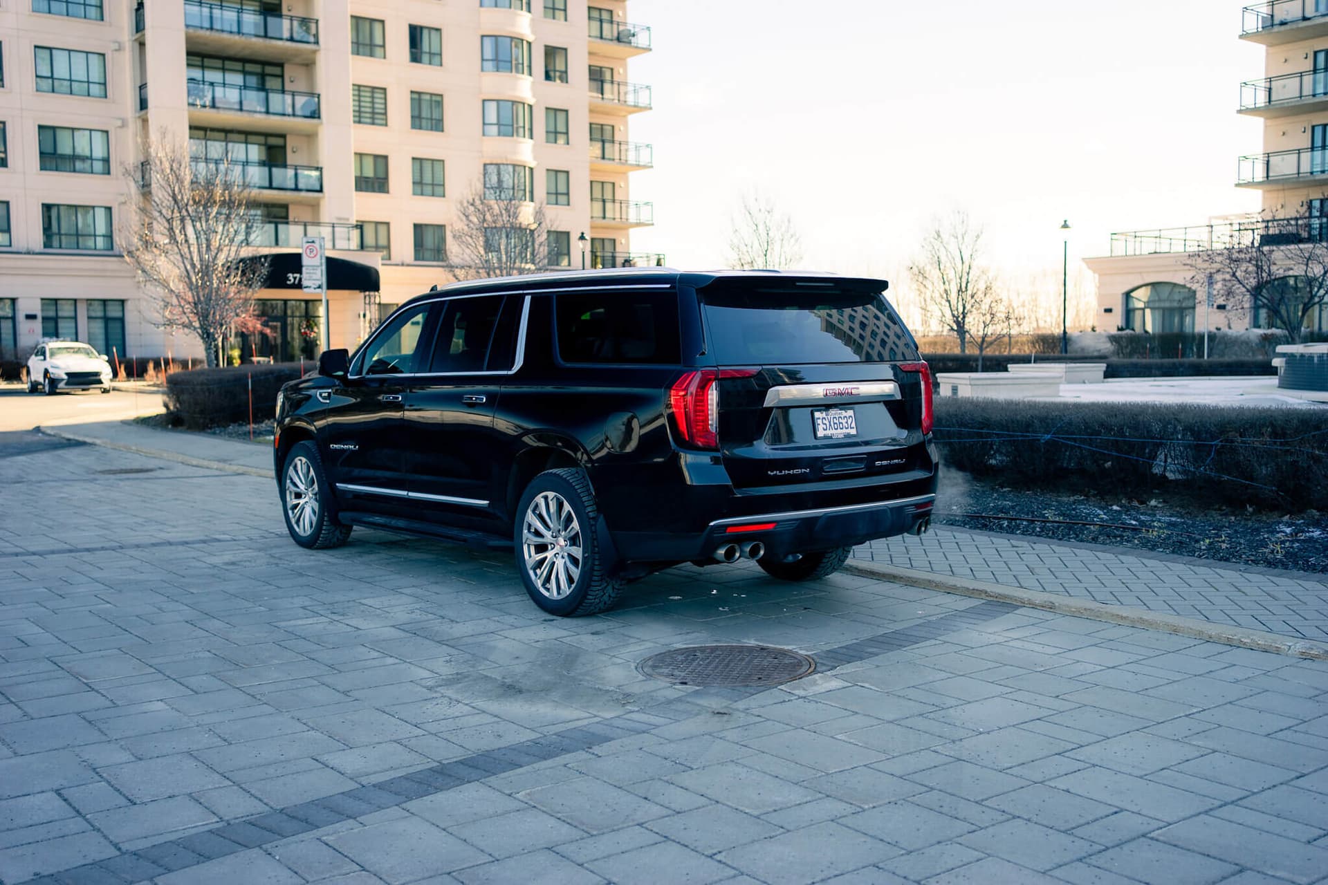 Black GMC Yukon XL on a dark reflective floor with golden edge light — photo 3