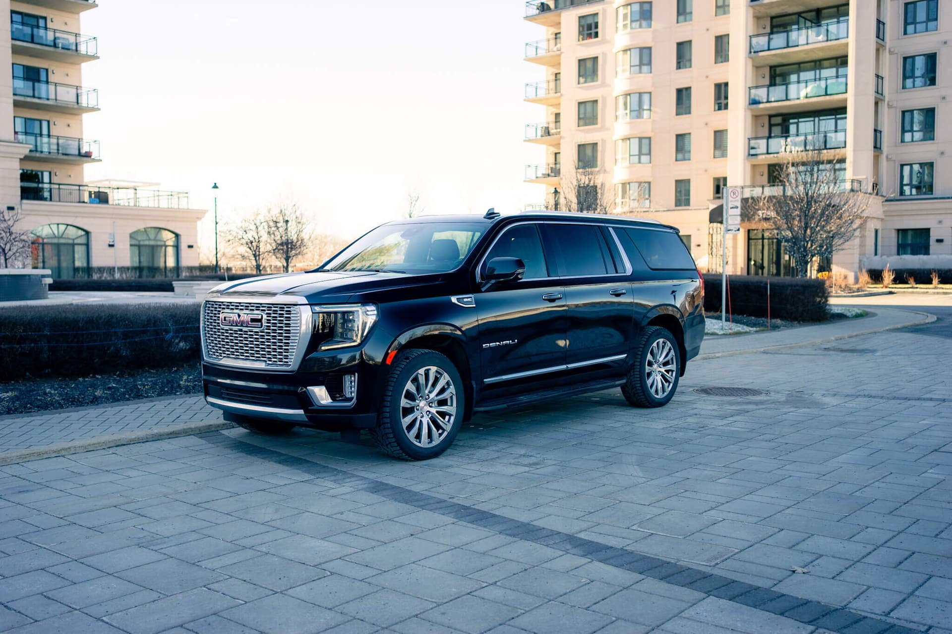 Black GMC Yukon XL on a dark reflective floor with golden edge light — photo 5